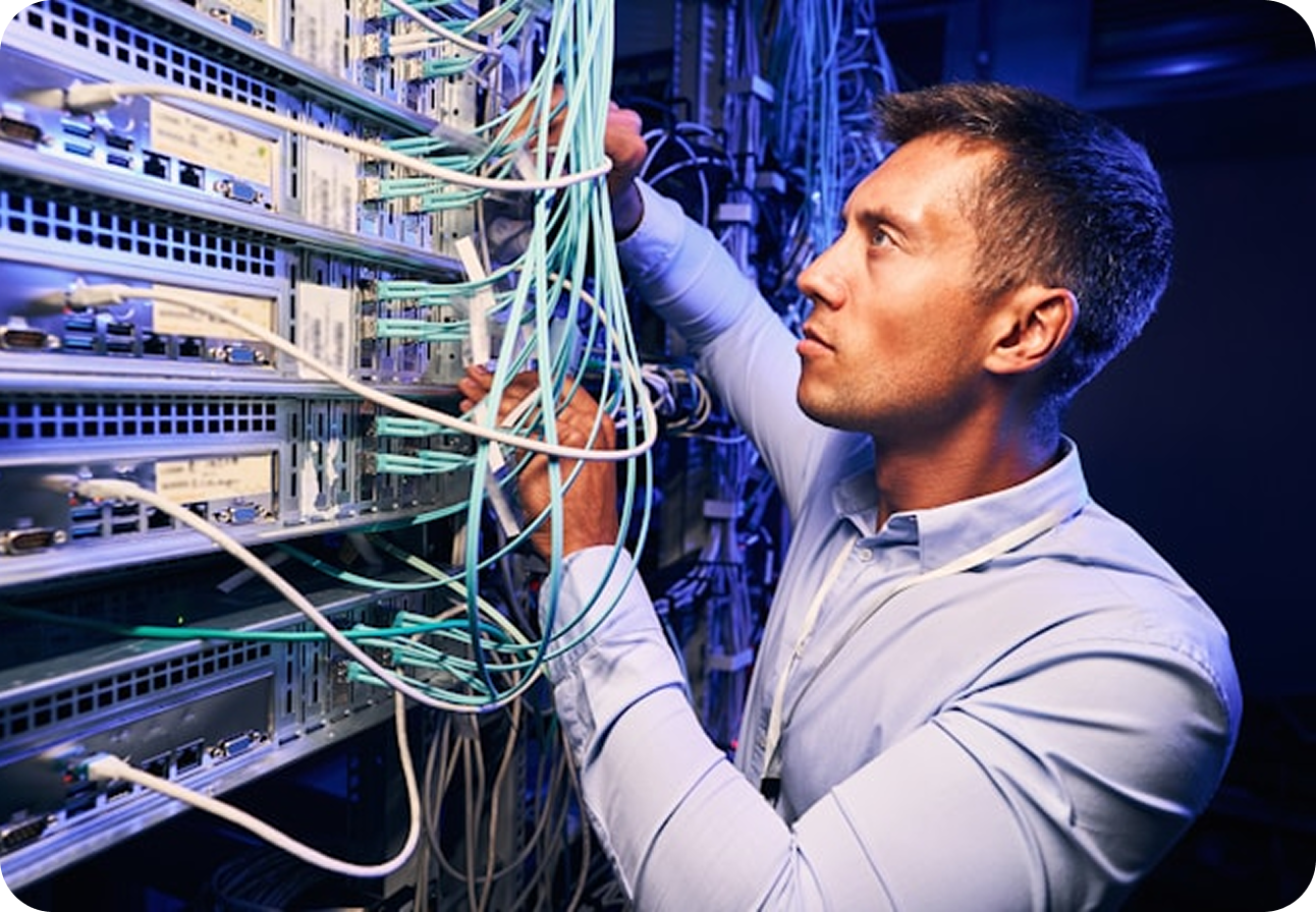 A technician in a data centre threading teal fiber optic cables into a server rack